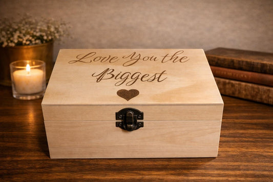 Wooden box with 'Love you the biggest' engraving on a wooden surface with a candle and books in the background.